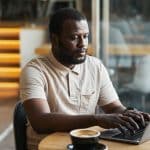 Black Man Using Laptop in Cafe