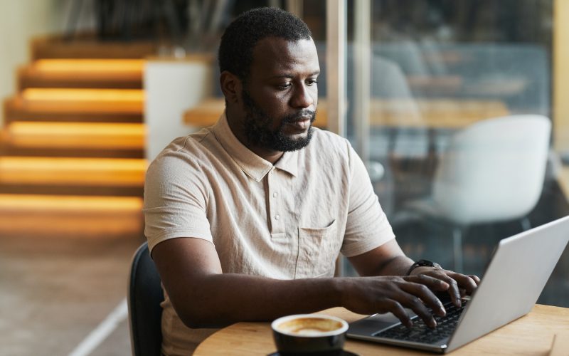 Black Man Using Laptop in Cafe