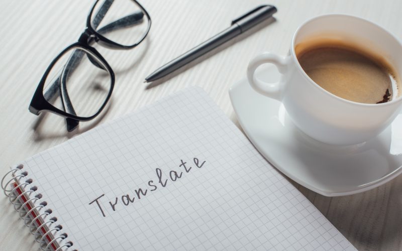 close up of coffee and notepad with word translate on workplace
